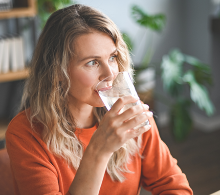 Young woman drinking glass of water concerned about her frequent urinary tract infections