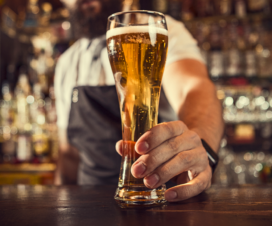 A male bartender handing over a glass of beer