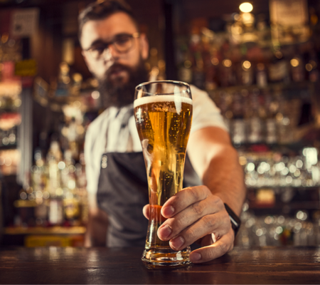 Bartender handing over a glass of beer wondering about alcohol affect on the body