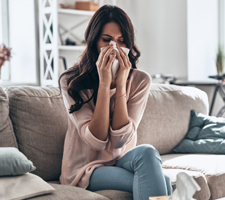 woman sneezing wondering when you should see an allergist