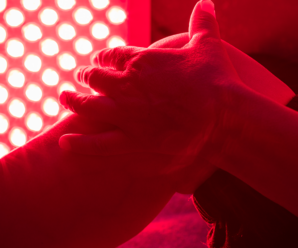 A person's bent leg with hand on it under a red light.