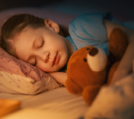A photo of a little girl sleeping with her teddy bear. 