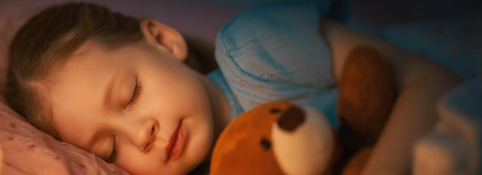 A photo of a little girl sleeping with her teddy bear.