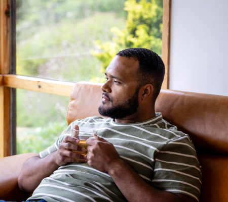 A man showing the signs of depression sitting and holding a coffee